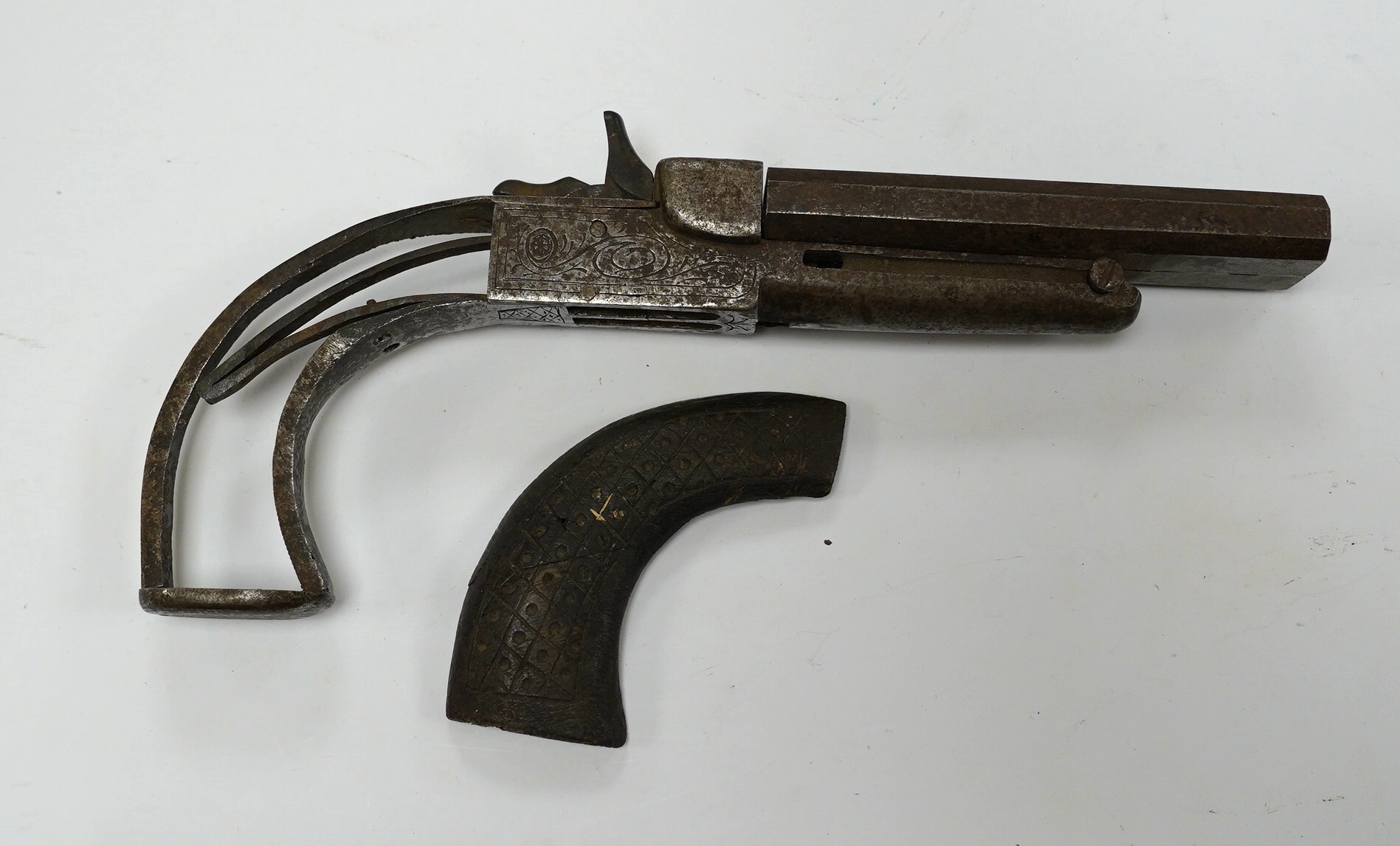 An early 19th century double-barrelled breach loading percussion pistol in relic condition, steel barrels, engraved frame, and walnut two piece grip, one piece missing, one piece detached, folding triggers, both missing